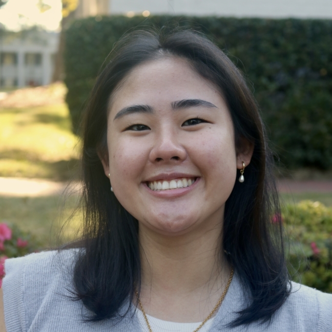 a young woman wearing a sweater vest with short dark hair