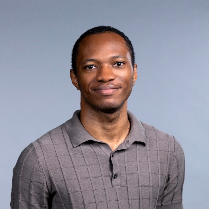 Young man with short black hair wearing a grey polo shirt