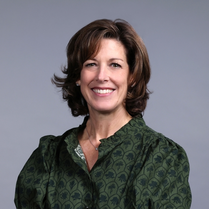 A woman with shoulder length brown hair and a green blouse