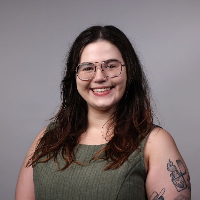 a professor with long dark hair wearing a green top and glasses