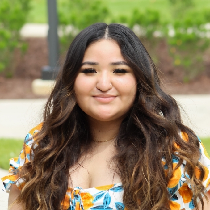 Headshot of young brunette woman with long hair and pleasant smile