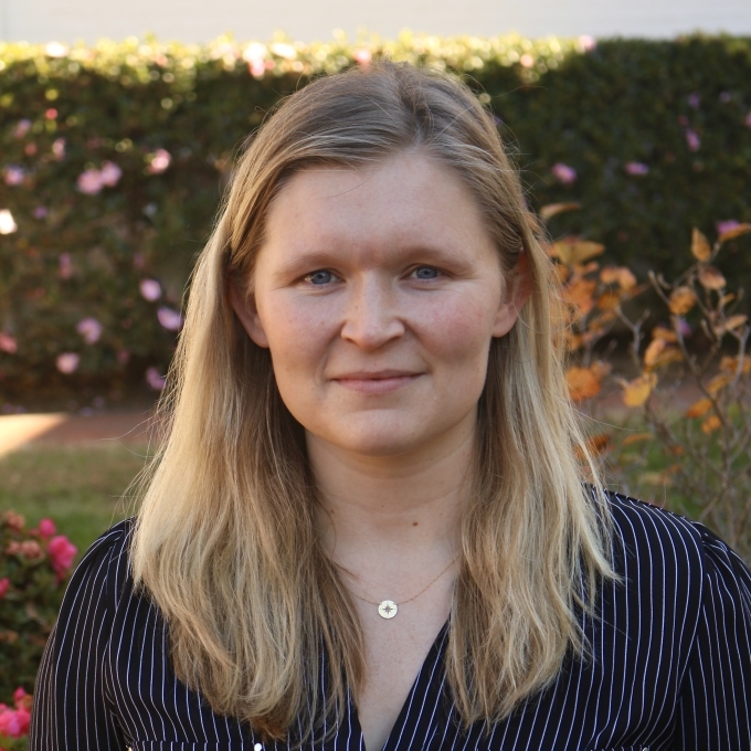 a white woman with blonde hair wearing a striped black top 