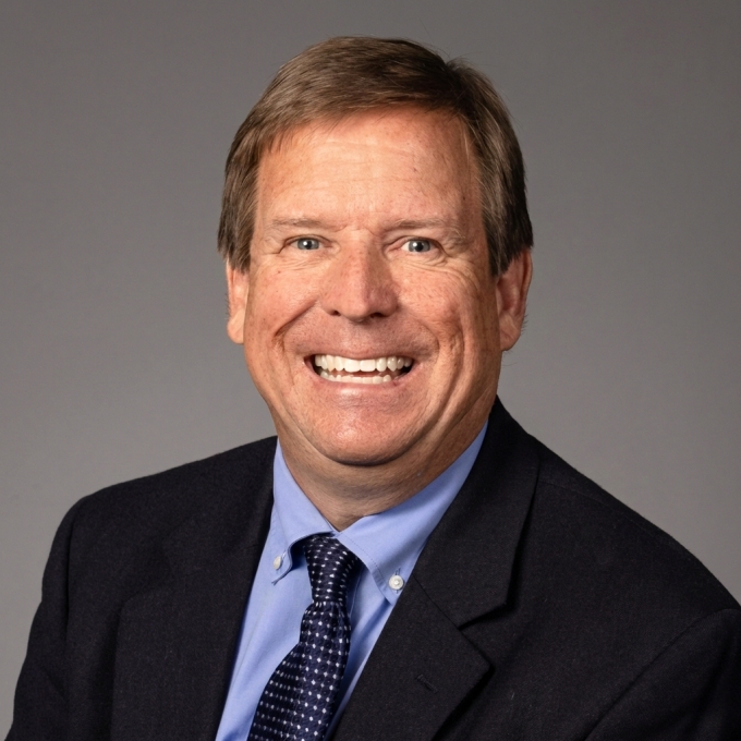 Smiling man of ~55 years old in tie and suit jacket with light brown hair