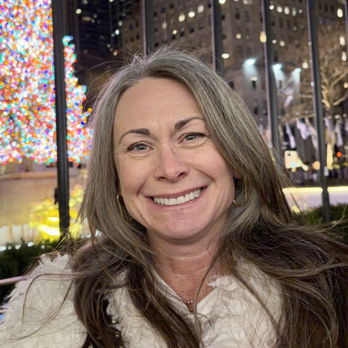 a woman with dark hair smiling outside at night while wearing a coat