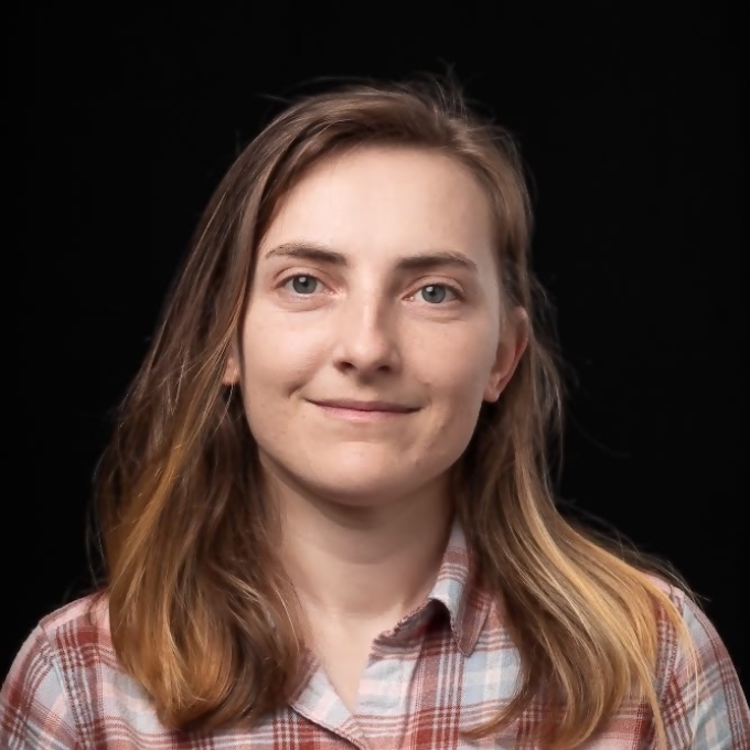 a young woman wearing a flannel shirt on a black background