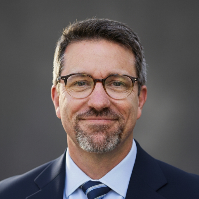 A man in a blue suit with glasses and a tie