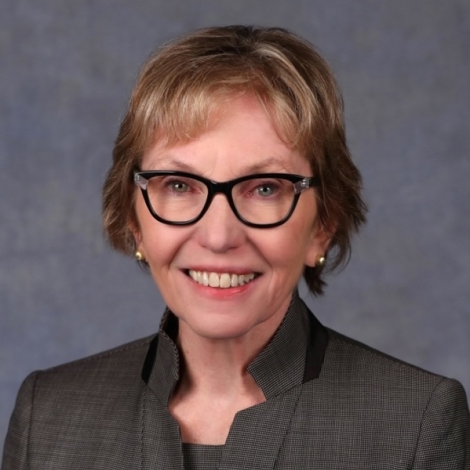 A white woman with blonde short hair and dark rimmed glasses