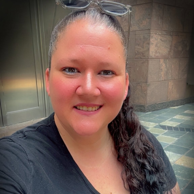 A caucasian woman with dark wavy hair in a ponytail