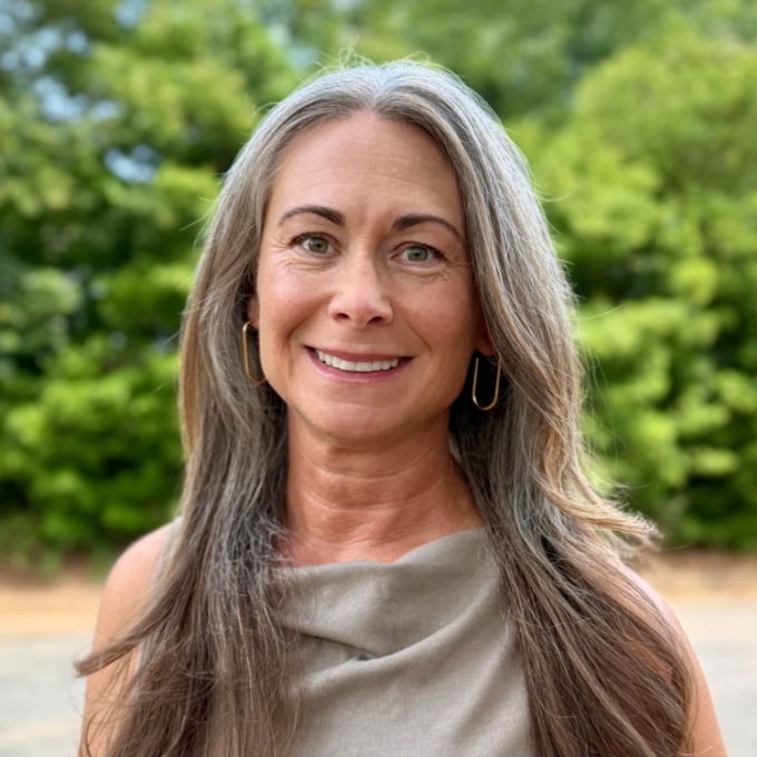 a woman with greying hair smiling outside