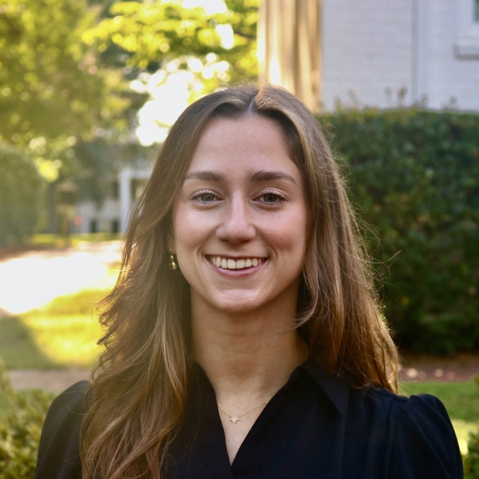 Ann smiling outdoors wearing a black button-up shirt with long brown hair