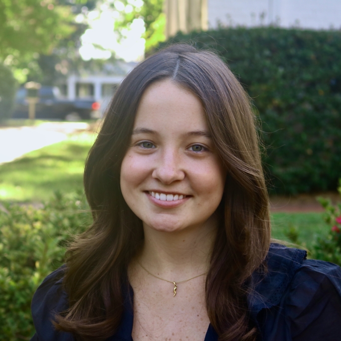 Annalee smiling outdoors with shoulder-length wavy dark hair and a black top.