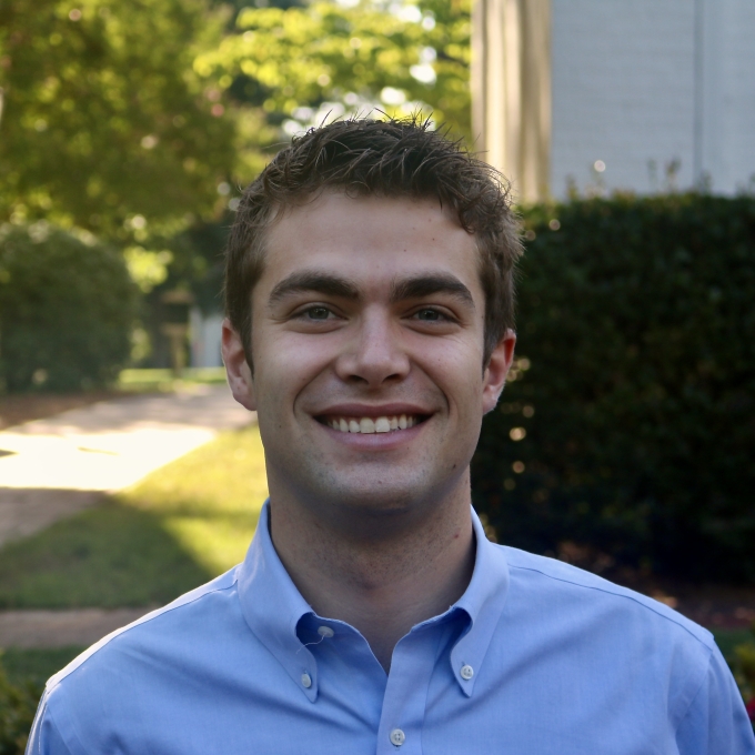 Will smiling outdoors in a light blue button-down shirt with short brown hair.