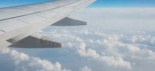 the wing of an airplane in the air over clouds
