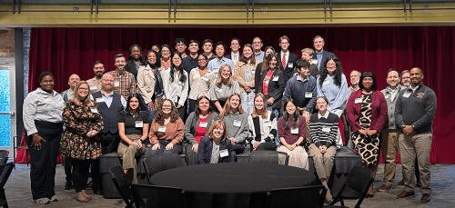 A large group of students, faculty and staff in front of a red curtain
