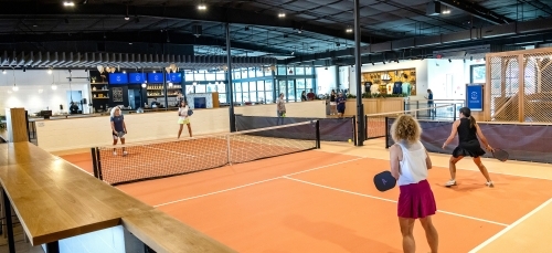 an indoor pickleball court where four people play