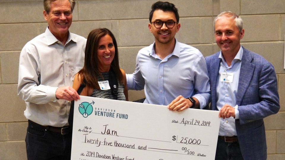 Shea Parikh and judges hold large check