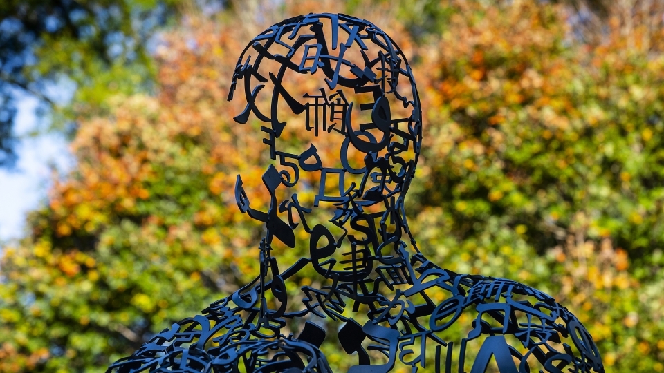 Campus sculpture with fall leaves in the background
