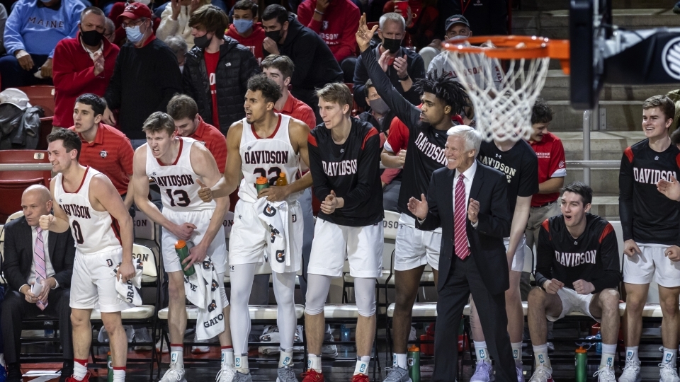 Davidson basketball players and Coach McKillop cheering on sidelines at a game