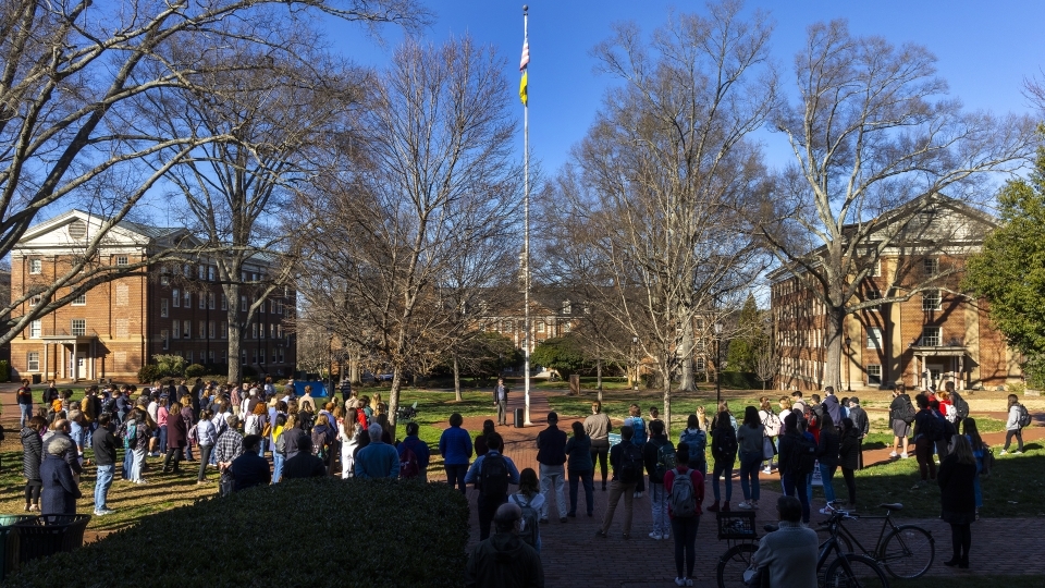 students cast in shade around the Chambers flagpole on a sunny day