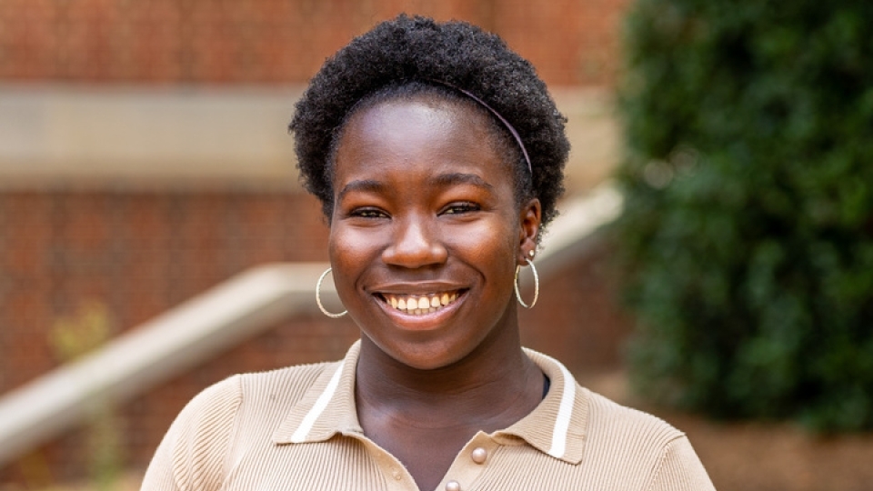 student smiling at camera wearing a beige polo