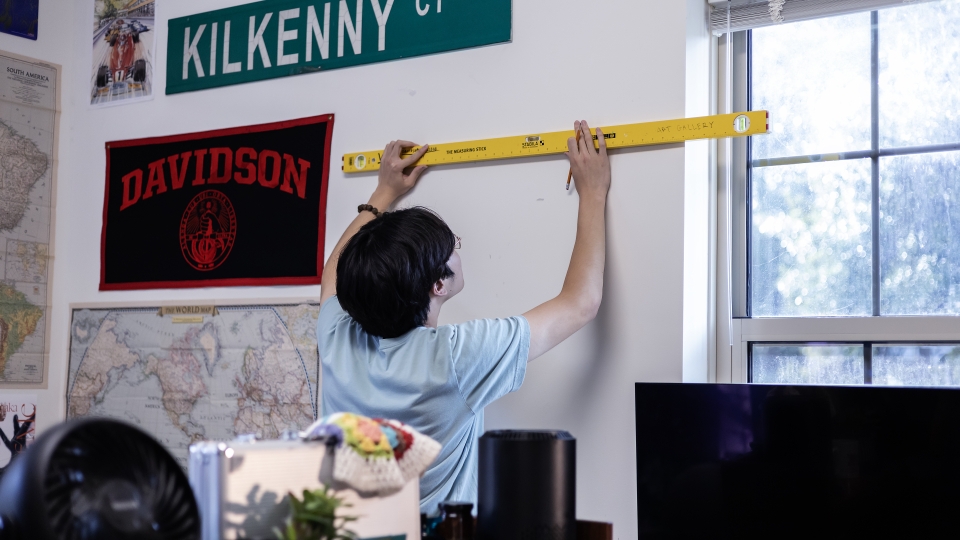 Student Hanging Artmate Art on Dorm Wall