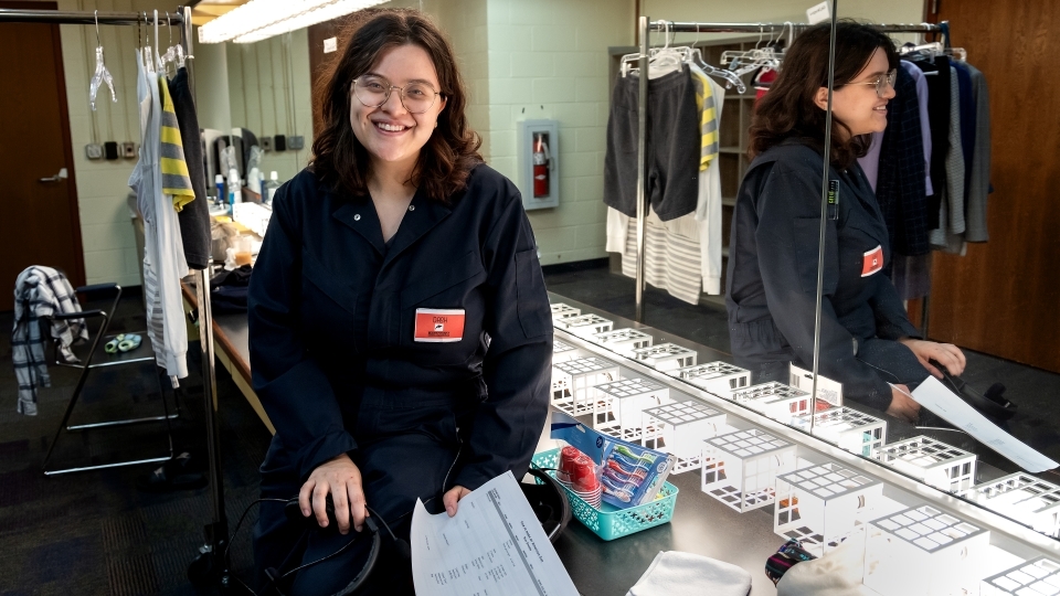 a young woman smiles while standing in a dressing room in front of a mirror