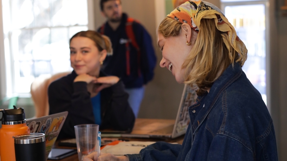 two students smile while working in a coffee shop