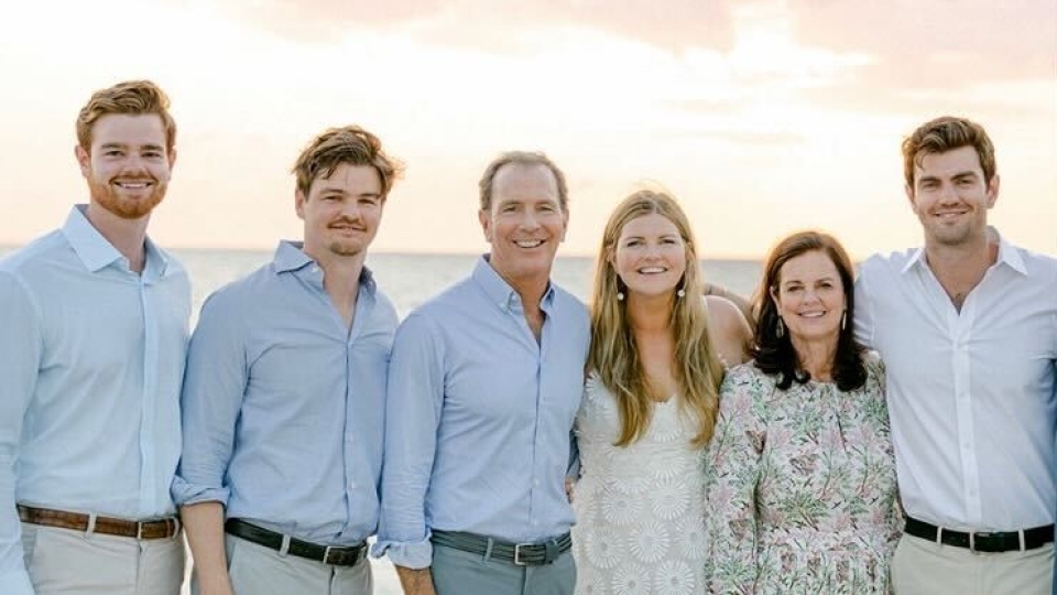 a family of six standing on a beach at dusk