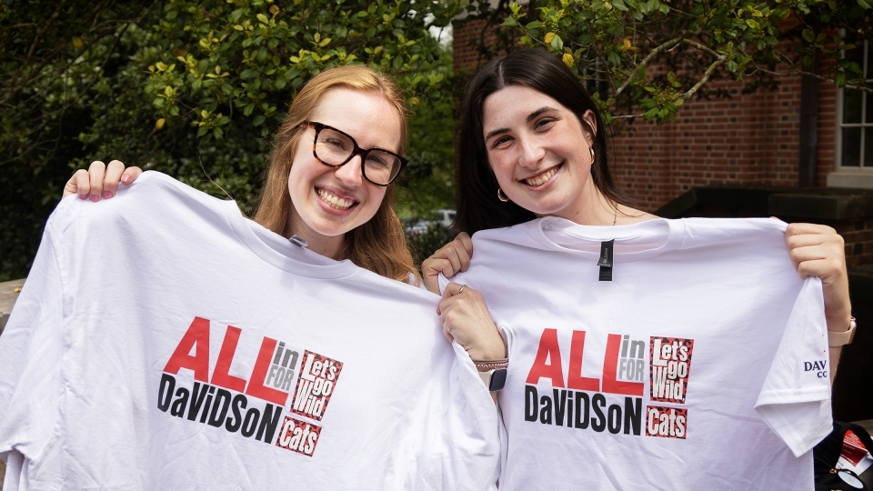 two young women holding white tee shirts