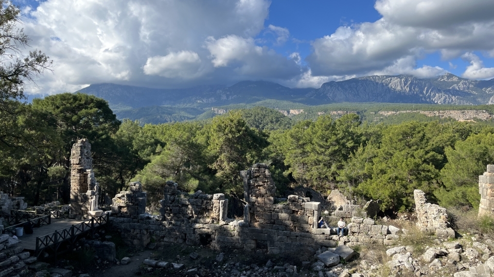 an ancient amphitheater with mountains and blue skies in the background