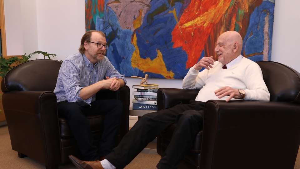 an older white man talking to another man