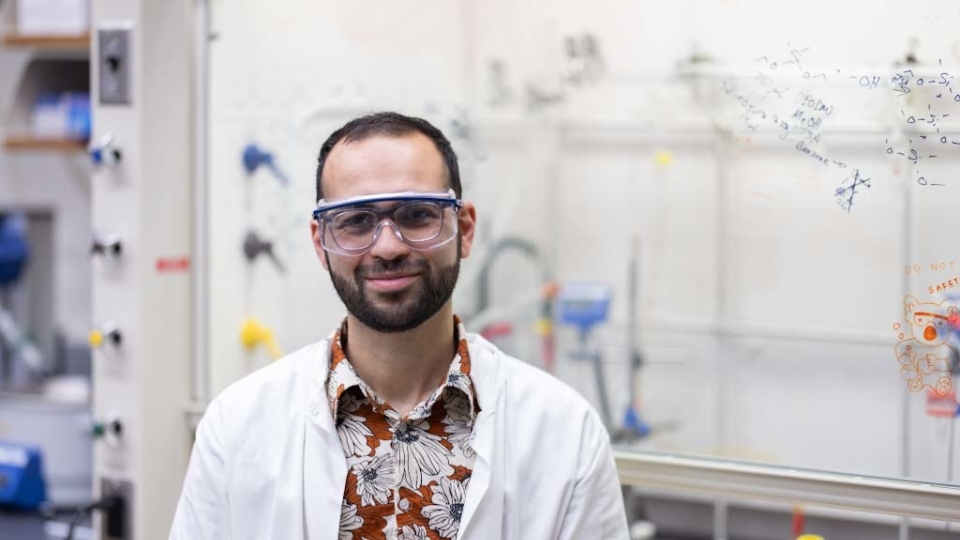 a young man wearing a lab coat over a hawaiian shirt in a lab
