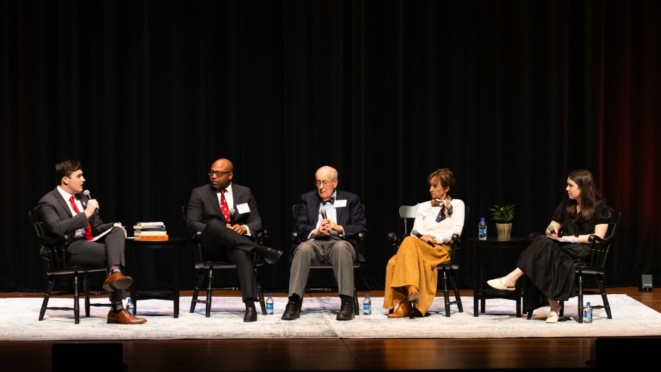 a young man speaks to a panel of alumni on a stage