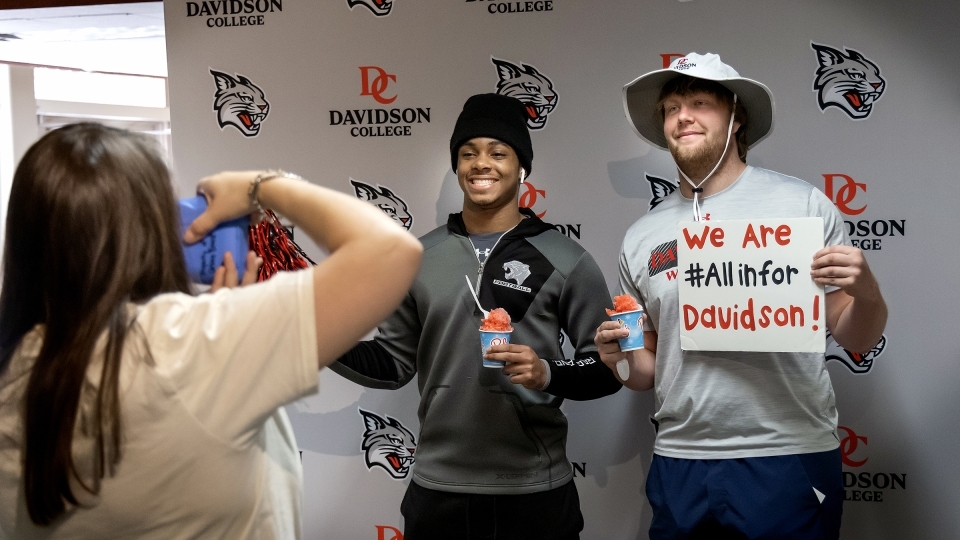 Two students pose with sno-cones and Davidson-themed signs at All In for Davidson