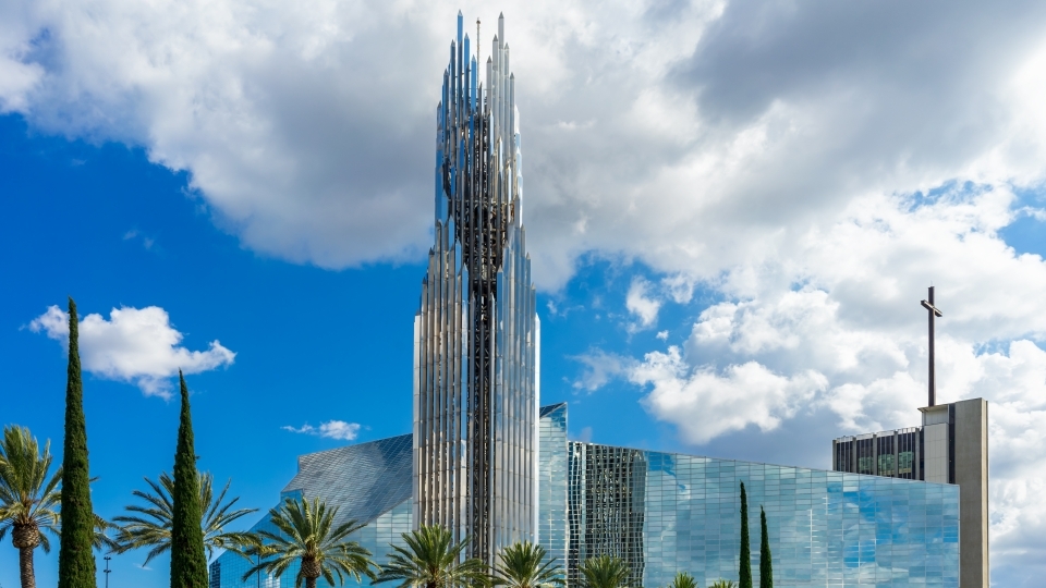 a large glass building surrounded by palm trees on a sunny day