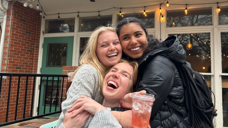 a group of young women smiling and holding a coffee