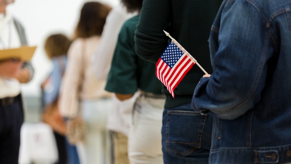 Person in line to vote holding American flag