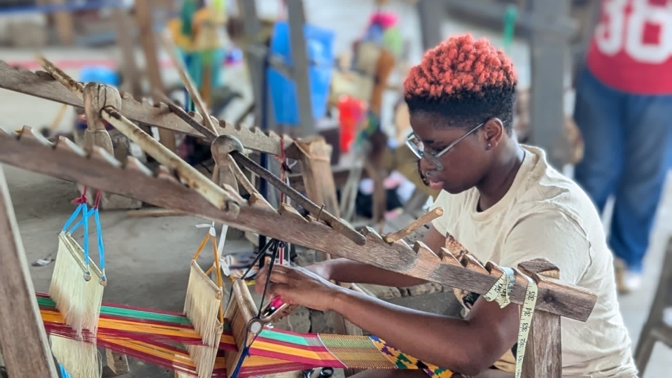 a young person works at a loom 