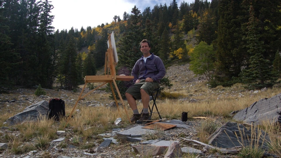 a young man paints in a forest