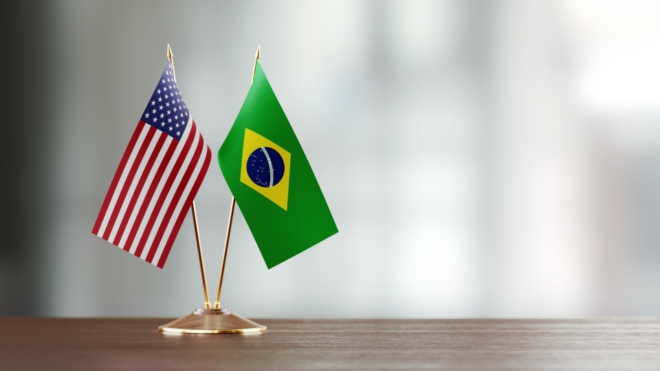 two small flags from the US and Brazil on a desk