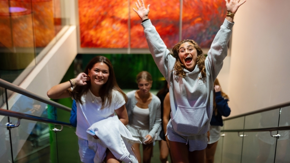 young women jump and smile in a museum
