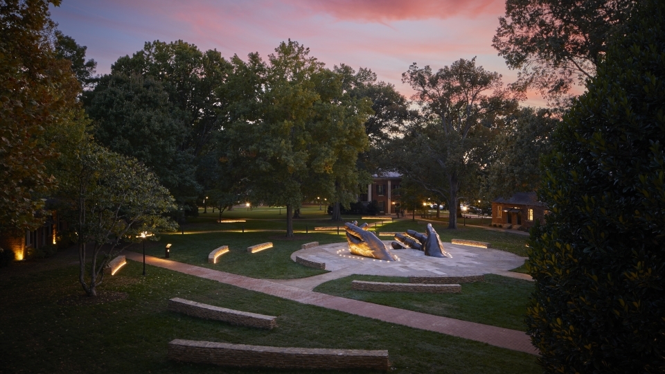 A sculpture in front of a colorful sunset on Davidson's Campus