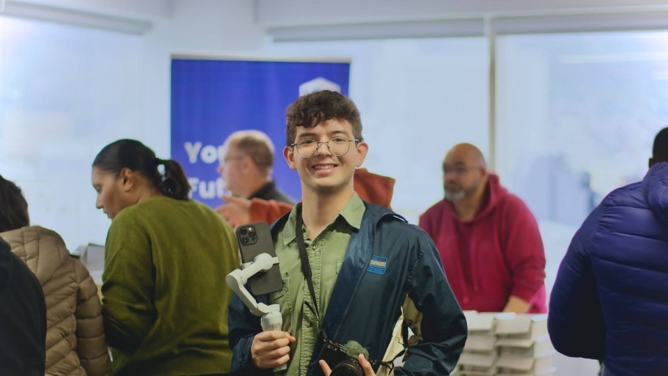 a young man with a camera and phone works media at an event