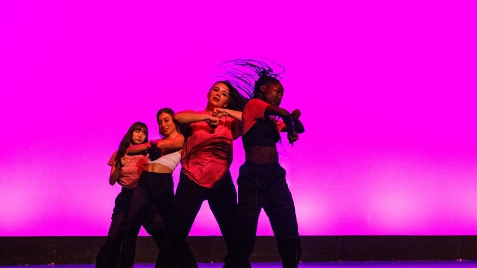 a group of your women dance onstage in front of a magenta backdrop