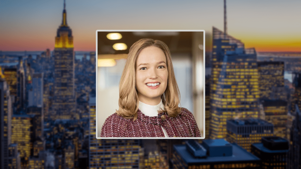 A headshot of a young blonde woman on a blurred skyline of NYC