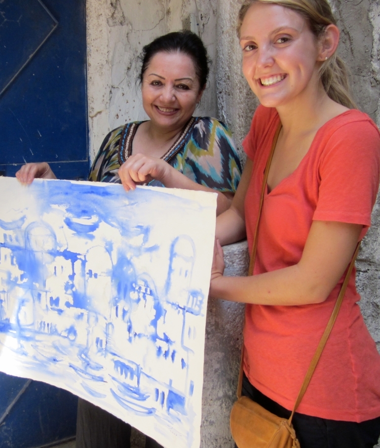 Student and Syrian artist hold watercolor painting.