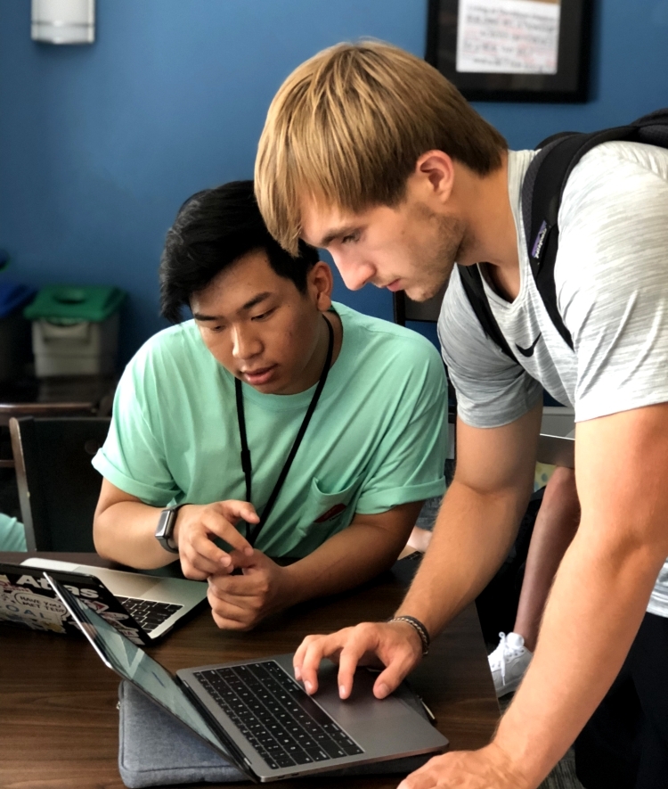 Technology & Innovation student tech helps student with his laptop