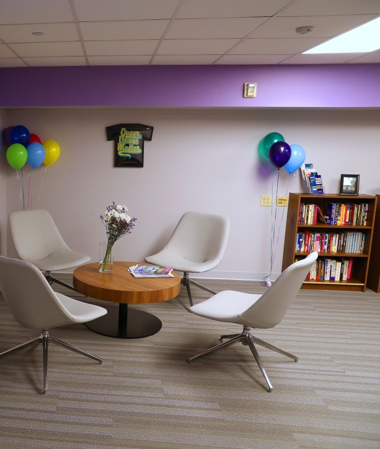 Lounge with lavender walls and sitting area, books, and tv