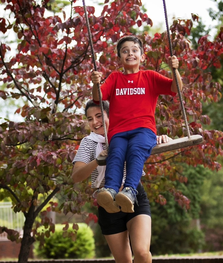 Person pushes child on swing