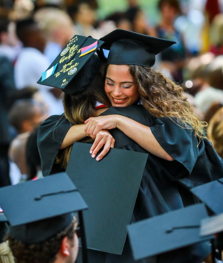 Students in regalia hug